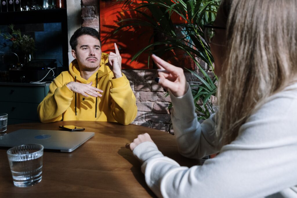 Teenager in yellow hooded jumper speaking to a woman